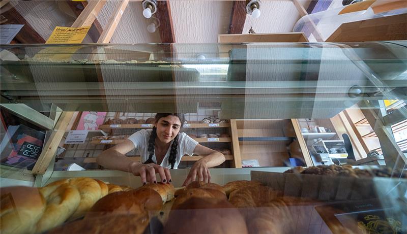 Eine Mitarbeiterin ordnet die Ware in der Theke des Verkaufsraums einer Bäckerei. Foto: Harald Tittel/dpa