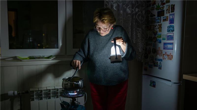 Eine Mutter kocht auf einem Gasbrenner nach einem Stromausfall in Kiew durch einen russischen Angriff.
