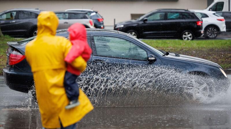 Eine Mutter und ihr Kind blicken auf eine teils überflutete Straße in Osnabrück.