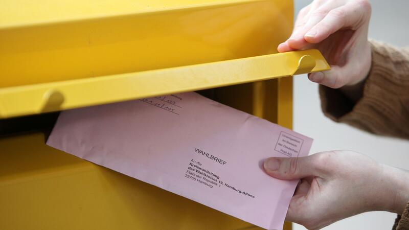 Eine Passantin steckt ihre Briefwahlunterlagen zur Bundestagswahl in einen Briefkasten in Hamburg.