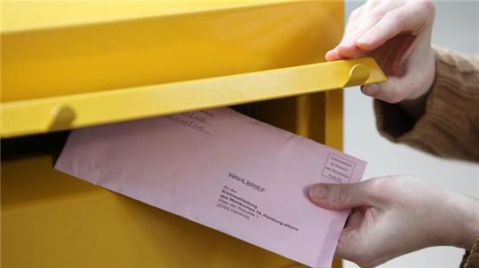 Eine Passantin steckt ihre Briefwahlunterlagen zur Bundestagswahl in einen Briefkasten in Hamburg.
