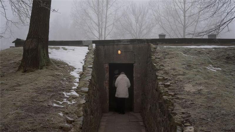 Eine Person betritt eine Gaskammer und ein Krematorium im ehemaligen nationalsozialistischen deutschen Konzentrations- und Vernichtungslager Auschwitz-Birkenau.