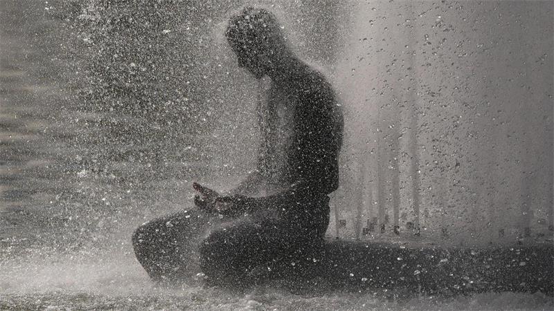 Eine Person erfrischt sich während der Hitzewelle in Paris in einem Brunnen in der Nähe des Eiffelturms.