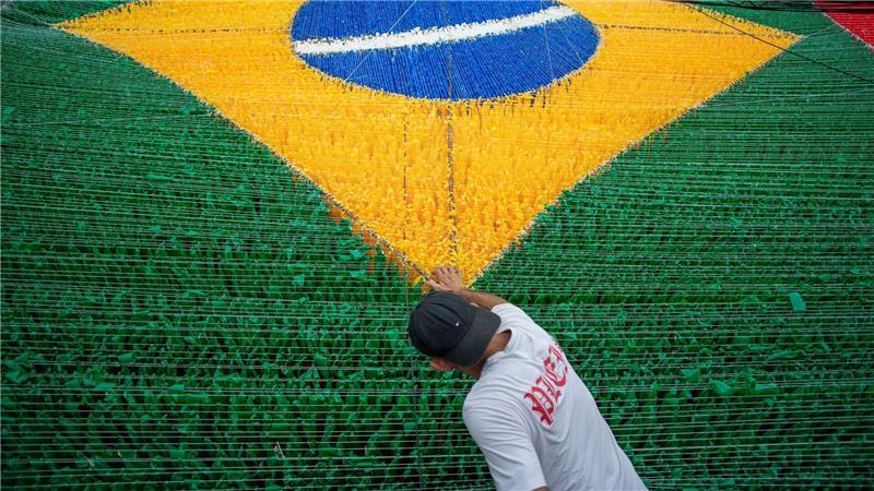 Eine Person gibt der hängenden Dekoration zur Feier der Fußballweltmeisterschaft 2026 auf der Rua 03 im Viertel Alvorada in Manaus, der Hauptstadt des brasilianischen Bundesstaates Amazonas, den letzten Schliff.