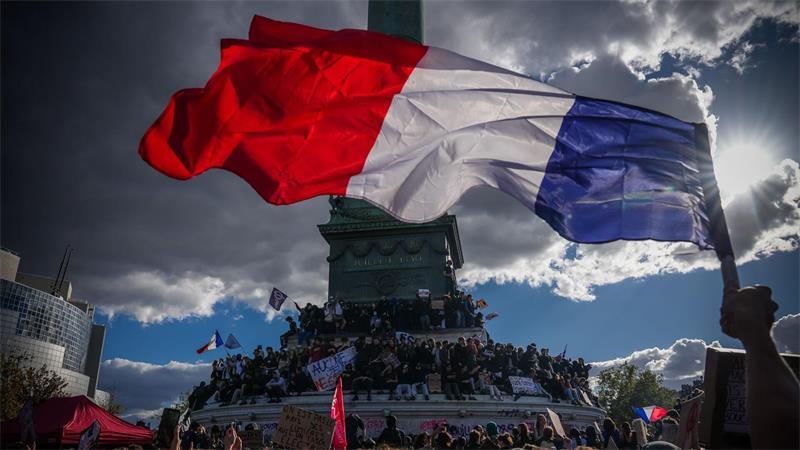 Eine Person hält bei einer Demonstration in Paris gegen unterfinanzierte Schulen eine französische Nationalfahne.