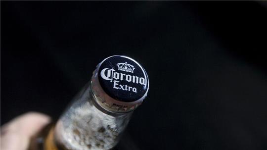 Eine Person hält eine Flasche des mexikanischen Corona-Biers in der Hand. Die Biermarke wird künftig auch in Sachsen-Anhalt in der „Hasseröder“-Brauerei hergestellt.