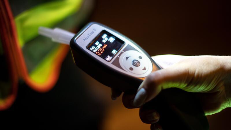 Eine Person hält einen Alkoholtester in der Hand