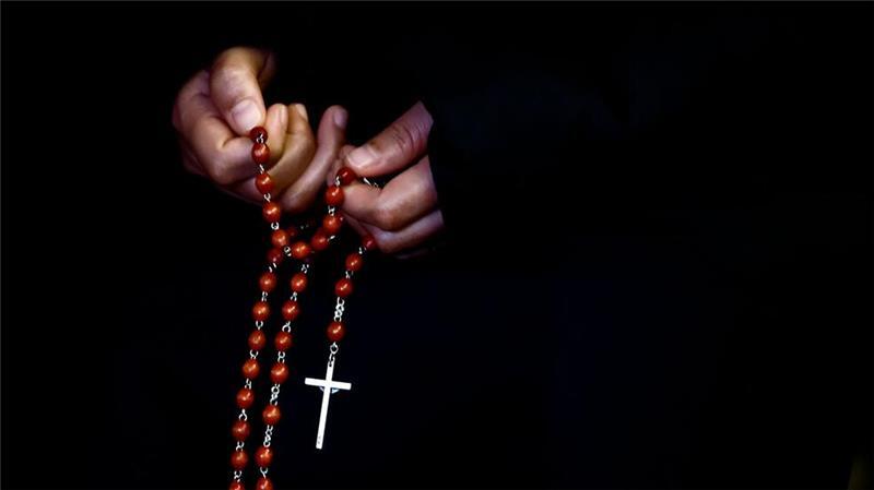 Eine Person hält einen Rosenkranz bei einem Gebet auf dem Petersplatz für die Gesundheit des Papstes.