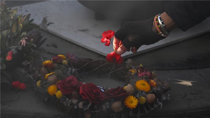 Eine Person legt eine Mohnblume an der Gedenkstätte „Für unser Land“ während der Gedenkfeier für Aborigines und Torres-Strait-Insulaner (ATSIVA) im Rahmen des Anzac-Tags am Australian War Memorial in Canberra nieder.