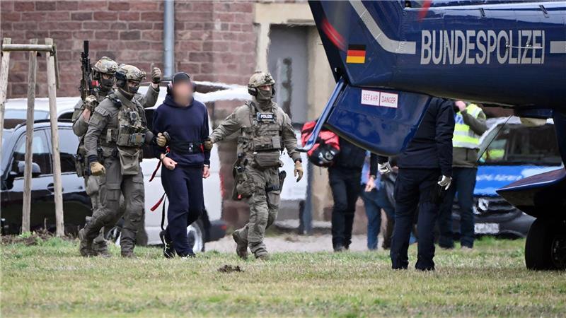 Eine Person wird von Polizeibeamten zu einem Hubschrauber gebracht.