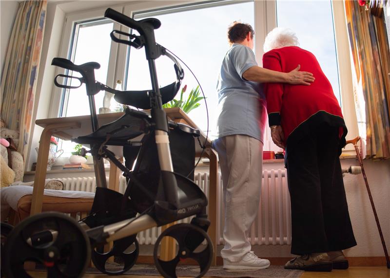 Eine Pflegerin (l) und eine Bewohnerin des Pflegeheims schauen zusammen aus einem Fenster im Wohnbereich des Pflegeheims. Foto: Tom Weller/dpa