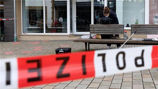 Eine Polizeibeamtin der Kriminaltechnik steht an einem abgesperrten Tatort.