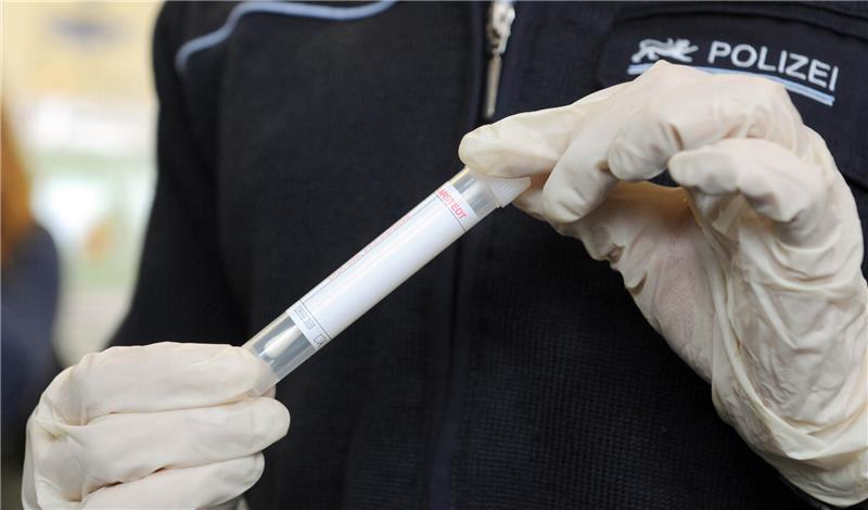 Eine Polizistin hält ein Wattestäbchen für eine DNA-Probe (Symbolbild). Foto: picture alliance / dpa