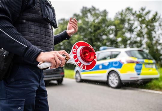 Eine Polizistin hält eine Winkerkelle in der Hand.