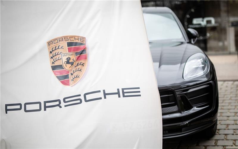 Dieselskandal: Gericht weist Millionenklage gegen Porsche SE ab Eine Porsche-Flagge weht am Firmensitz in Stuttgart-Zuffenhausen vor einem Porschewagen.