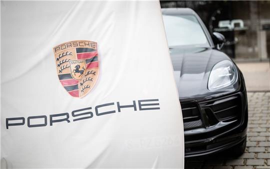 Eine Porsche-Flagge weht am Firmensitz in Stuttgart-Zuffenhausen vor einem Porschewagen.