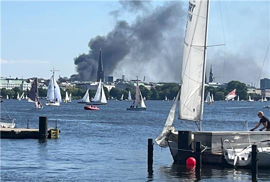 Eine Rauchwolke ist über der Alster in Hamburg zu sehen. Auf einem zehnstöckigen Haus in der Hamburger HafenCity ist es am Freitagnachmittag zu mehreren Explosionen gekommen. Foto: Britta Pedersen/dpa