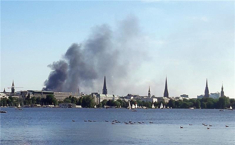 Großbrand sorgt für Rauchwolke in Hamburger Hafencity Eine Rauchwolke ist über der Alster in Hamburg zu sehen. Auf einem zehnstöckigen Haus in der Hamburger HafenCity ist es am Freitagnachmittag zu mehreren Explosionen gekommen. Foto: Désirée Ballhausen/-/dpa