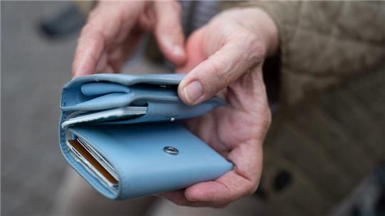 Eine Rentnerin hält ein Portemonnaie in der Hand. Reicht das Geld diesen Monat?