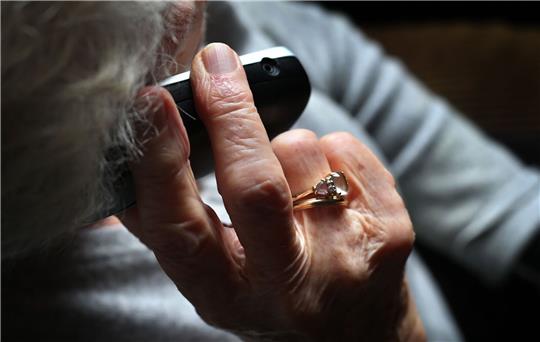 Eine Rentnerin hält ein Telefon in der Hand. Foto: dpa