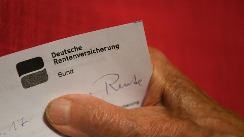 Eine Rentnerin hält ihren Rentenbescheid in der Hand.