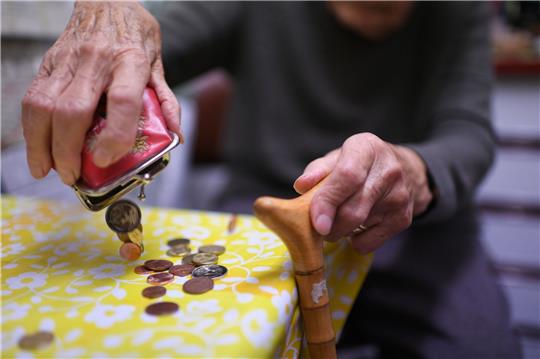 Eine Rentnerin schüttet den Inhalt ihres Geldbeutel auf den Küchentisch.