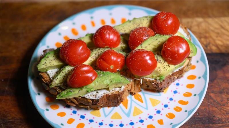 Essen gehen immer teurer: Deutschland isst Stulle Eine Scheibe Kürbiskernbrot mit Avocado und Tomaten. Viele jüngere Leute in Deutschland sehen sich eher als Avocadobrot- denn Wurstbrot-Typ. (Symbolbild)