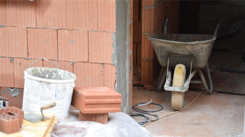 Die Zahlen sind eindeutig: Bauland wird in der Krise nicht billiger Eine Schubkarre, Steine, Maurerkelle und ein Mörteleimer stehen auf einer Baustelle.