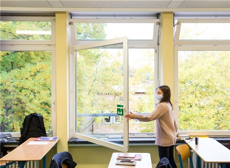 Eine Schülerin einer 13. Klasse der Oberstufe der Stadtteilschule Niendorf öffnet mit einer Mund-Nasen-Bedeckung im Deutsch-Unterricht das Fenster. Foto: Bockwoldt/dpa