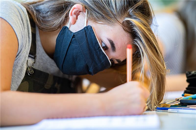 Eine Schülerin sitzt im Unterricht mit einem Mund-Nasen-Schutz. Foto: Guido Kirchner/dpa