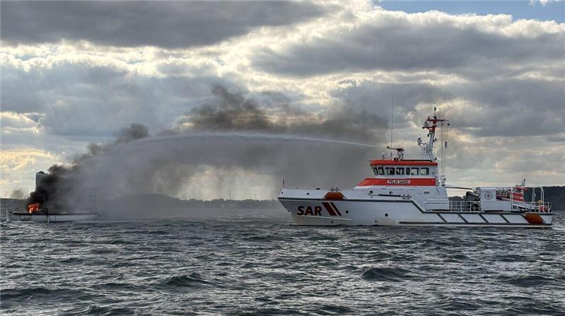 Ein Schiff der DGzRS  löscht ein Feuer auf einer Segelyacht. 