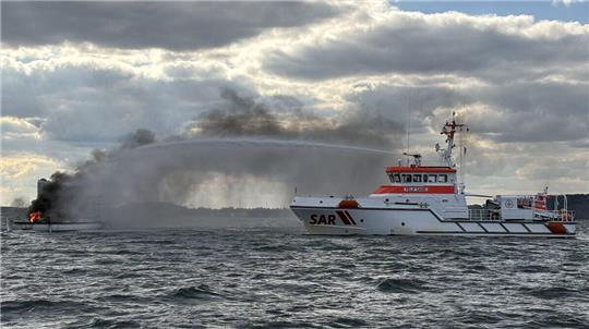 Ein Schiff der DGzRS  löscht ein Feuer auf einer Segelyacht. 