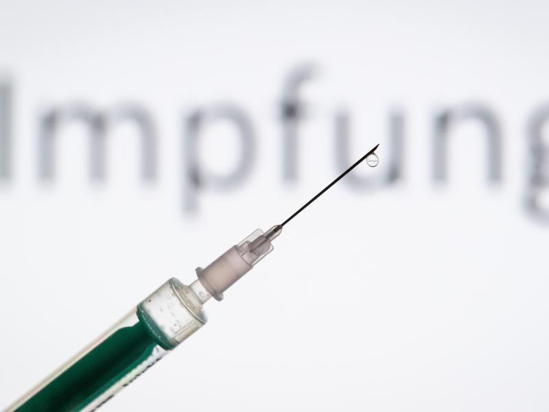 Eine Spritze wird vor den Schriftzug «Impfung» gehalten. Foto: Friso Gentsch/dpa/Archivbild