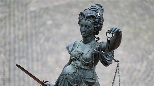 Eine Statue der Justitia hält eine Waage und ein Schwert in der Hand.