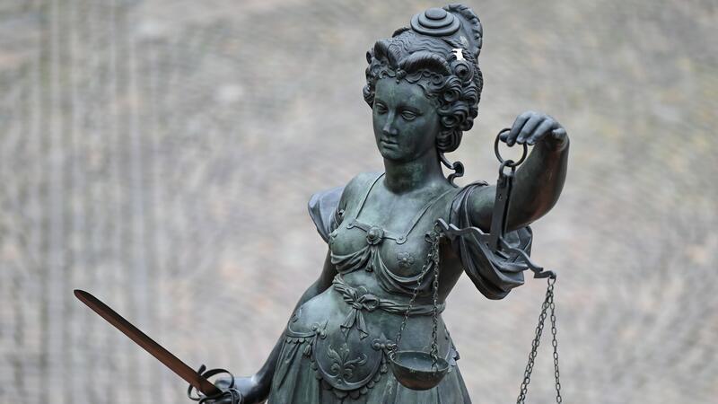 Eine Statue der Justitia hält eine Waage und ein Schwert in der Hand.