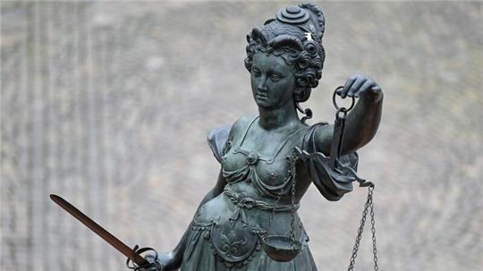 Eine Statue der Justitia hält eine Waage und ein Schwert in der Hand.