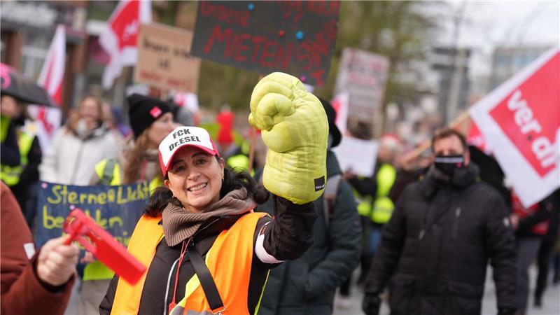 Eine Teilnehmerin der Kundgebung reckt einen übergroßen Handschuh in die Höhe. 
