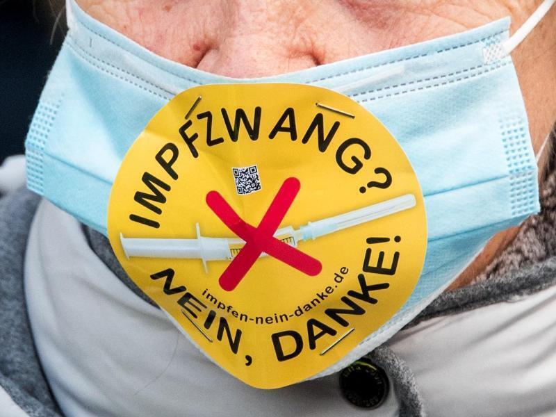 Eine Teilnehmerin einer Demonstration in Hamburg mit einem Mundschutz und der Aufschrift "Impfzwang? Nein, danke!". Foto: Daniel Bockwoldt/dpa