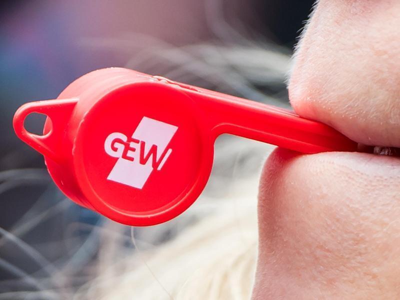 Eine Teilnehmerin eines Warnstreiks bläst in eine Trillerpfeife mit dem Logo der Gewerkschaft GEW. Foto: Daniel Bockwoldt/dpa/Archivbild