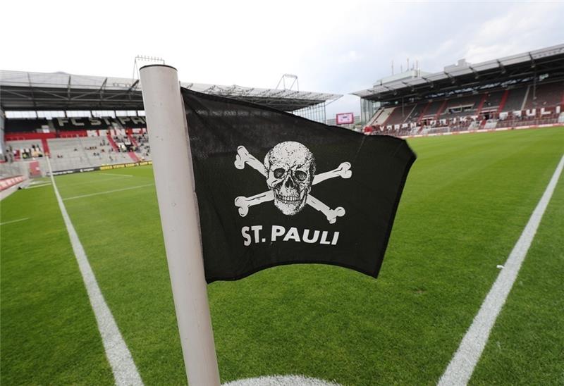 Eine Totenkopfflagge mit dem Schriftzug "St. Pauli" flattert vor einem Spiel an einer Eckfahne im Wind. Foto: picture alliance / dpa