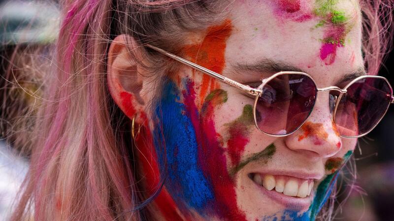 Eine Touristin bedeckt ihr Gesicht mit farbigem Puder während der Holi-Feierlichkeiten in Nepal. Das Fest hat auch international viele junge Fans gefunden.