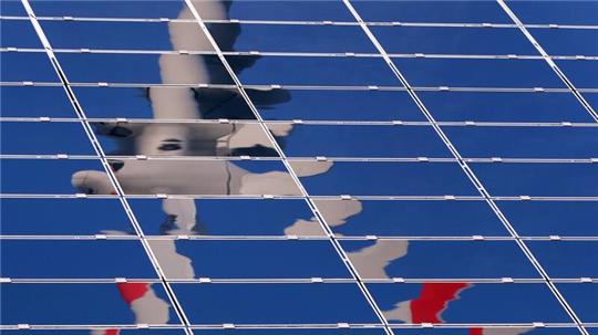 Eine Windkraftanlage spiegelt sich in Photovoltaikmodulen. Damit Buxtehude seine Klimaschutzziele erreicht, sind Windräder und Solarparks notwendig.