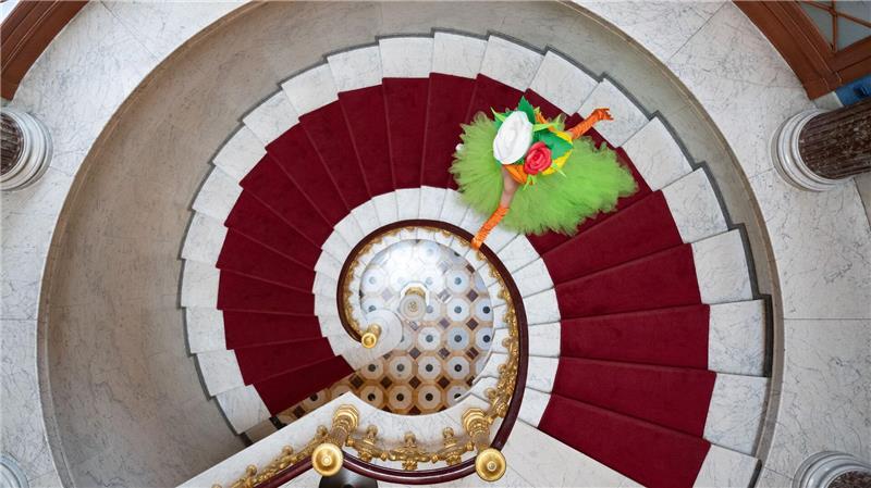 Eine als Blumenmädchen verkleidete Darstellerin geht am Rande einer Pressekonferenz zur Dresdner Schlössernacht im Schloss Albrechtsberg über eine Treppe. 