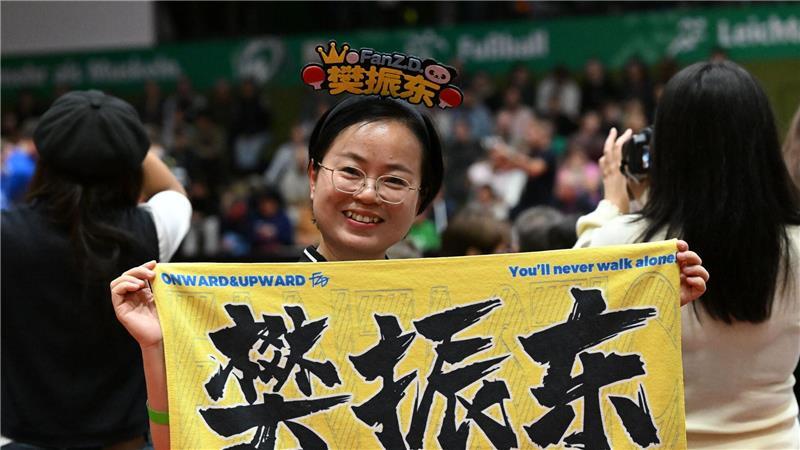Eine chinesische Anhängerin hält beim Bundesliga-Spiel zwischen Werder Bremen und dem 1. FC Saarbrücken ein chinesisches Fanplakat hoch.