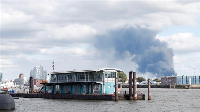 Große Rauchsäule über Veddel: Feuer im Hamburger Hafen – Drei Verletzte Eine große Rauchwolke ist hinter dem Hafen zu sehen, links die Elbphilharmonie.