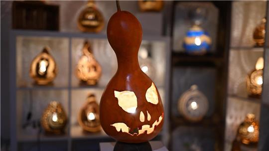 Eine handgefertigte Lampe aus einem Flaschenkürbis - mit Halloween-Fratze.