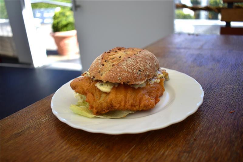 Eine knusprige, orangene Panade aus Kichererbsenmehl ummantelt das Backfischbrötchen im Elbfischer in Jork-Wisch.