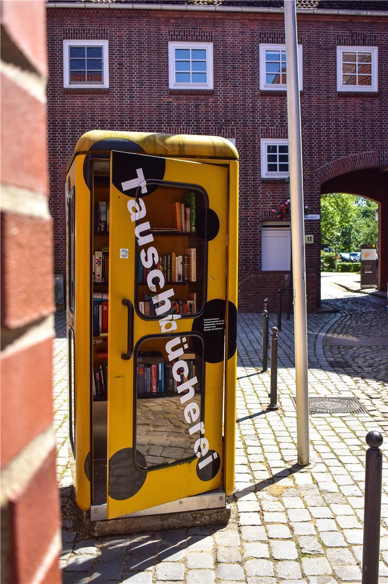 Hollywoodreif: Mit ChatGPT auf Entdeckungsreise durch Buxtehude Eine alte, gelbe Telefonzelle, die jetzt eine Tauschbücherei ist.