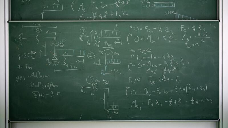 Eine mathematische Berechnung steht mit Kreide geschrieben an einer Tafel.