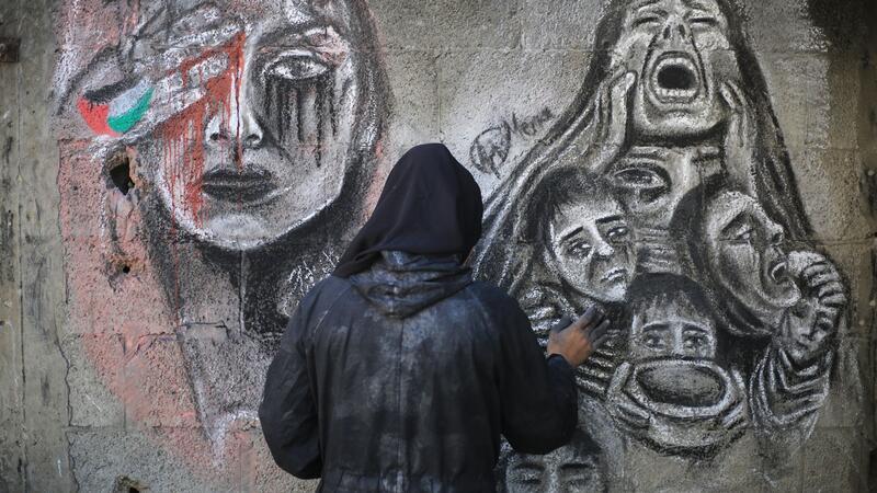 Eine palästinensische Künstlerin bemalt mit Kohle die Wände einer Schule in Deir al-Balah im Zentrum des Gazastreifens, in die sie umgesiedelt wurde.